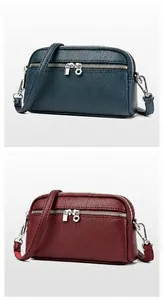 Gros plan d'un petit sac bandoulière à double zip en cuir texturé au grain de litchi