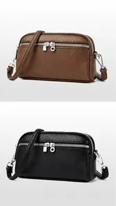 Détail des sacs à bandoulière café et noir en cuir grainé avec double fermeture éclair