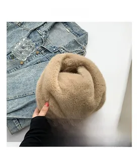Close-up of soft camel plush bucket bag with fine metal chain on denim jacket