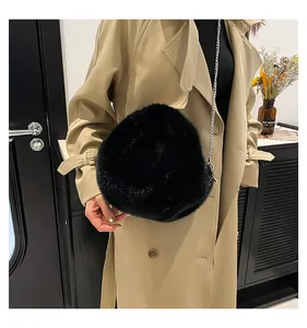 Detail of round black faux fur bucket bag with silver metal chain strap and soft texture