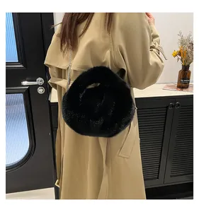 Detail of soft black faux fur bucket bag with metal chain strap on khaki trench coat
