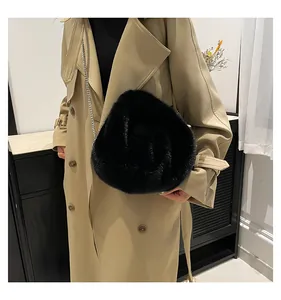 Detail of black faux fur cloud bag with silver chain strap worn over a khaki trench coat