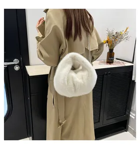 Detail of white faux fur crossbody bag featuring soft texture and silver chain strap