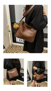 Détail du sac seau en cuir marron foncé avec logo mode et pendentif ours en peluche