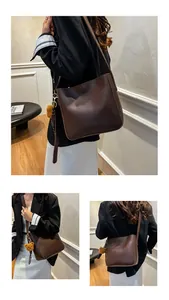 Détail du sac seau en cuir marron foncé avec un charmant pendentif d'ours en peluche
