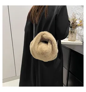 Detail of beige faux fur crossbody bag with silver chain strap on a wooden surface