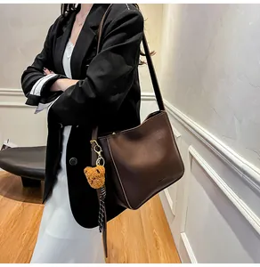 Détail du grand sac cabas en cuir marron foncé avec un ourson en peluche et un ruban en soie