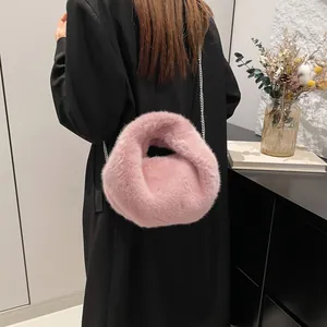 Chic pink faux fur bucket bag with silver chain strap shown on model's shoulder