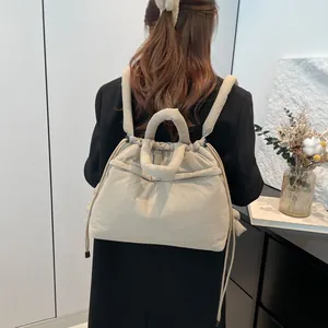Quilted beige puffer backpack with drawstring closure for women shown on casual black coat