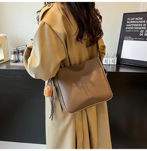 Gros plan sur un sac seau vintage en cuir marron foncé avec charme ours et texte mode