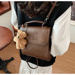 Dettaglio zaino vintage in pelle PU marrone con ciondolo a forma di orso e logo inciso