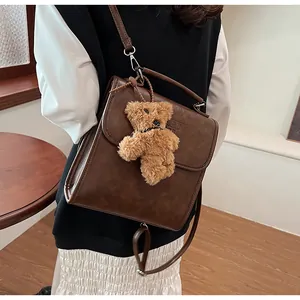 Dettaglio dello zaino marrone vintage con ciondolo a forma di orso e fibbie argentate