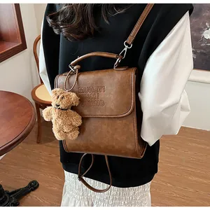 Dettaglio dello zaino vintage in pelle marrone con ciondolo a forma di orso sul modello