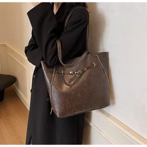 Dettaglio borsa tote grande in pelle marrone scuro con anelli metallici e zip laterali