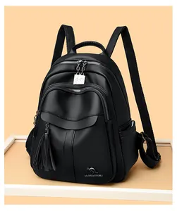 Close-up of black pebbled leather backpack detail with tassel and silver metal logo