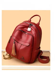 Detailed view of red pebble leather backpack with decorative tassels and multi-zipper pockets