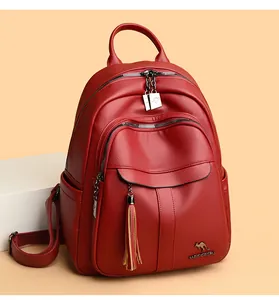 Close-up of red leather backpack featuring tassel charms and multiple zipper pockets