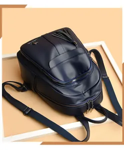 Detail of navy blue leather backpack featuring fringe tassel zipper and gold kangaroo logo