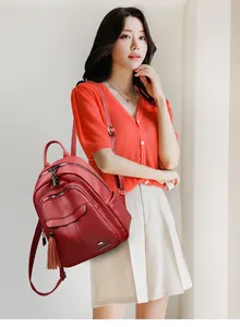 Detail of red pebbled leather backpack with tassel charm and metallic kangaroo logo