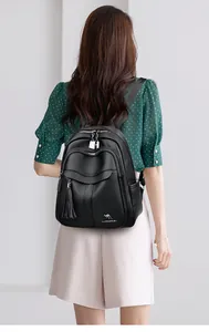 Detail view of women's black leather backpack with tassel charms and kangaroo logo