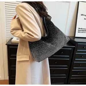 Detalle de un bolso tote negro con pedrería llevado por una modelo en un interior