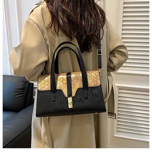 Detail of snake-embossed flap and gold twist lock on the two-tone crossbody bag