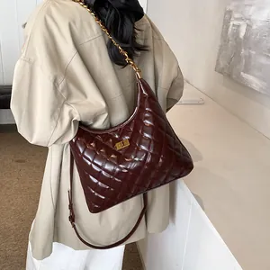 Quilted saddle bag in glossy dark brown leather with golden chain strap on a model