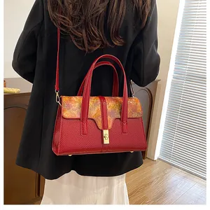 Detail of burgundy textured leather shoulder bag with vintage floral print flap and gold lock