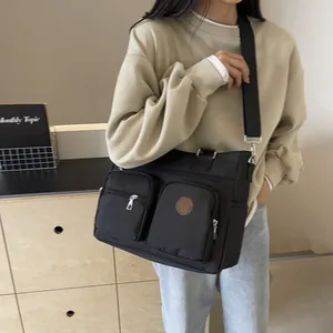 Retro black nylon tote bag with dual front pockets and wide strap for outdoor sports