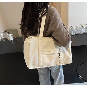 Large beige nylon travel tote bag worn on shoulder in a minimalist lifestyle setting