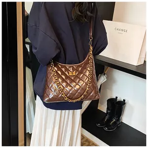 Close-up of deep brown quilted shoulder bag with gold chain and glossy diamond texture