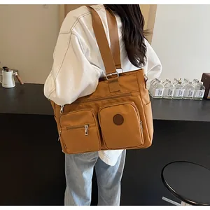 Close-up of caramel nylon tote bag with dual front pockets and wide shoulder strap detail