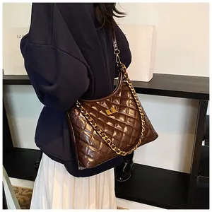 Dark brown quilted hobo bag with glossy finish and gold chain strap shown on model
