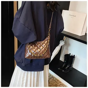 Detailed side view of brown quilted saddle bag featuring gold chain and thin shoulder strap