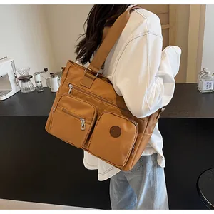 Detail of large brown multi-pocket tote bag showing durable nylon texture and broad strap