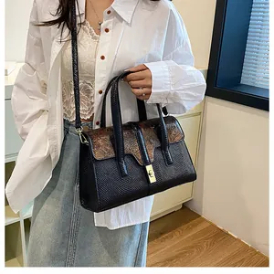 Fashionable black shoulder bag with brown print flap and golden metal clasp on a model