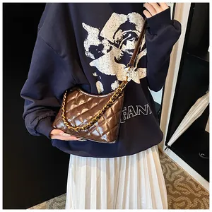 Detail of dark brown quilted leather saddle bag with gold chain strap on a model
