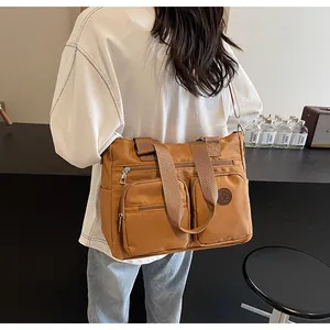 Detail view of brown nylon tote bag with functional zipper pockets and durable handles