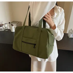 Large olive green nylon tote bag carried by a model as a versatile shoulder travel bag