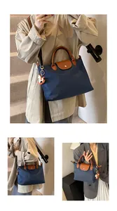 Detail of navy nylon tote bag showing brown leather handles and a horse-shaped charm