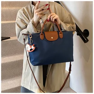 Detail of navy nylon tote bag with leather flap and orange horse charm on stairs