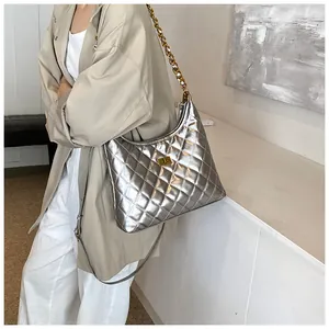 Detail of silver quilted saddle bag featuring a metallic finish and gold chain strap