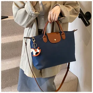 Detail of navy nylon tote bag with leather handles and an orange horse charm