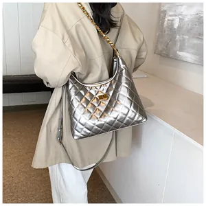 Silver quilted shoulder bag with gold chain strap and turn-lock on beige trench coat