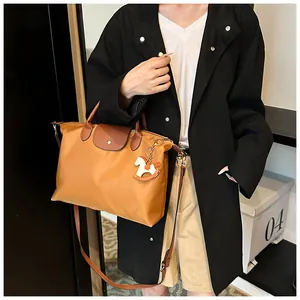Detail of tan nylon tote bag featuring brown leather flap and golden metallic clasp