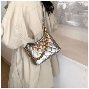 Silver quilted saddle bag with gold chain strap worn by a model in a beige trench coat