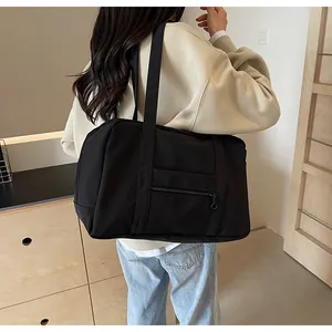 Rear view of a model carrying a large black nylon tote bag for travel, fitness and yoga