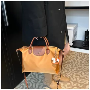Detail of a brown nylon tote bag with leather flap and horse charm on a person