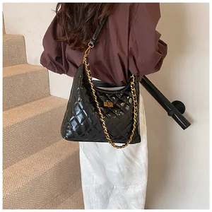 Close-up of quilted black saddle bag featuring gold chain strap and metal lock detail
