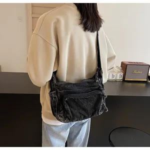 Detail view of black washed denim crossbody bag with multiple zipper pockets